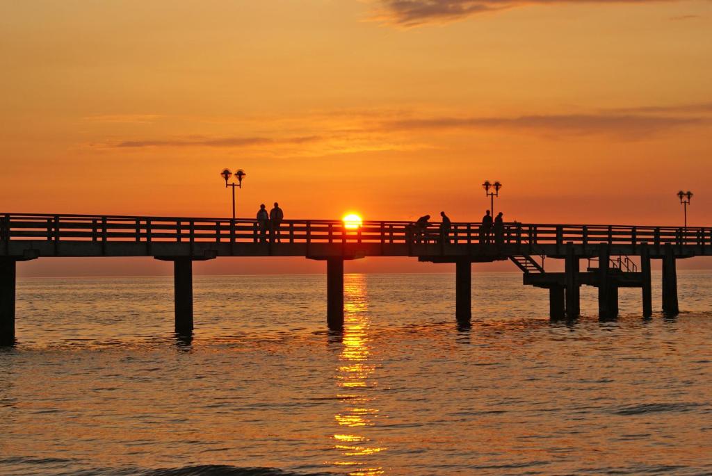 格拉尔-米里茨Ostsee Ferienwohnungen und Ferienhäuschen的水面上的一个有太阳的码头