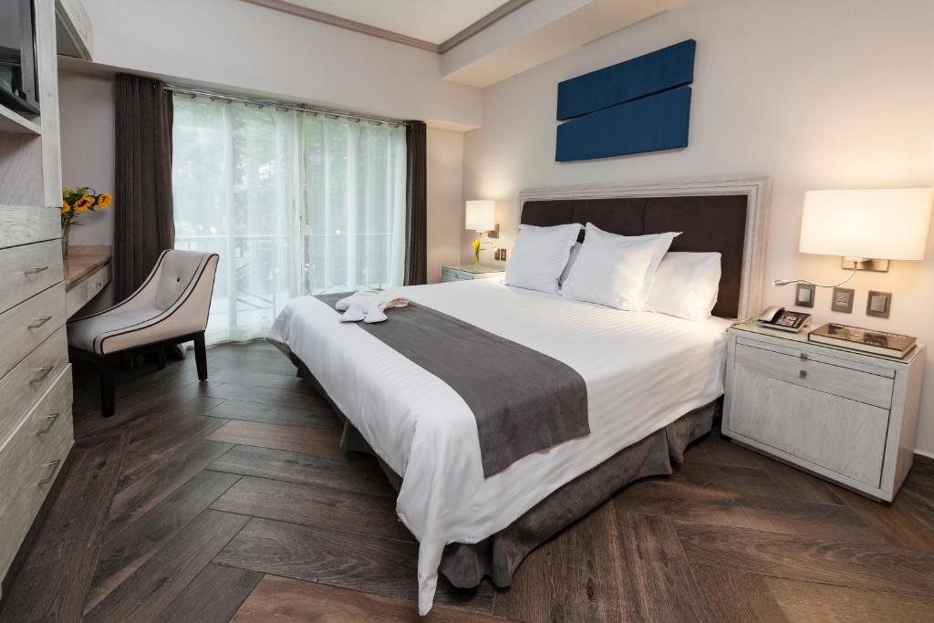 墨西哥城天使套房酒店的酒店客房带一张大床和一把椅子
