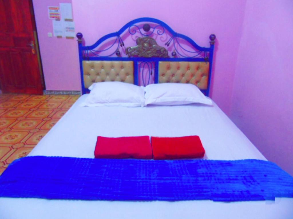特尔纳特岛爱妮民宿的床上有两个红色枕头的床