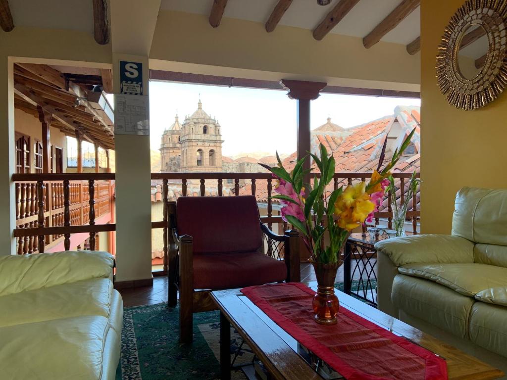 库斯科阿梅林迪亚酒店的客厅配有桌子,享有建筑的景色