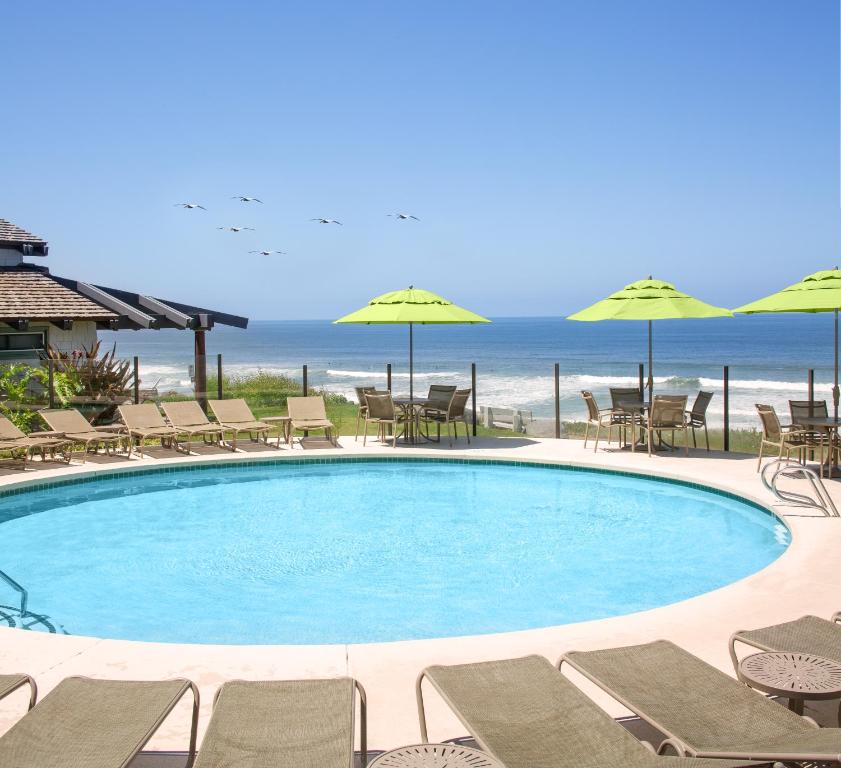 德尔马WCH at Wave Crest Resort的一个带椅子和遮阳伞的游泳池以及大海