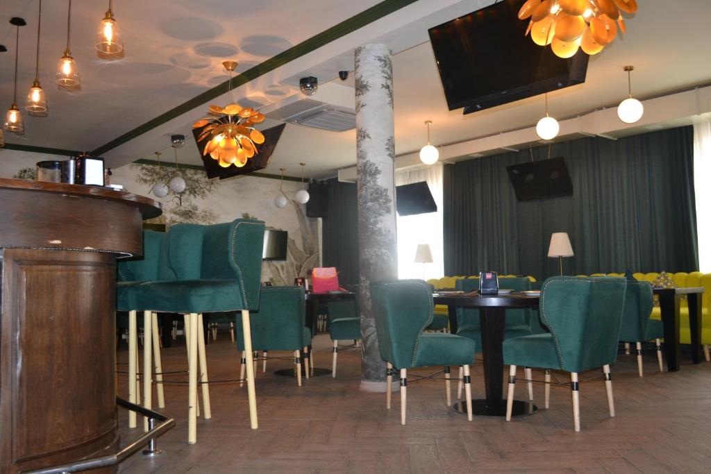 阿克托比Ayhan Hotel的一间带绿色椅子和桌子的餐厅以及一台电视