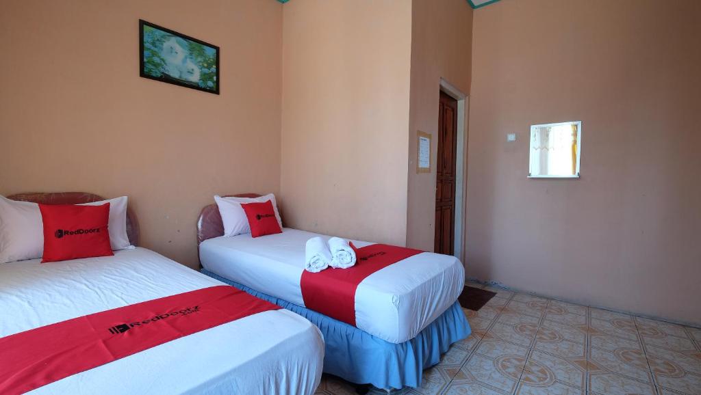 古邦RedDoorz near Mangrove Forest Kupang的一间设有两张红色和白色床单的房间