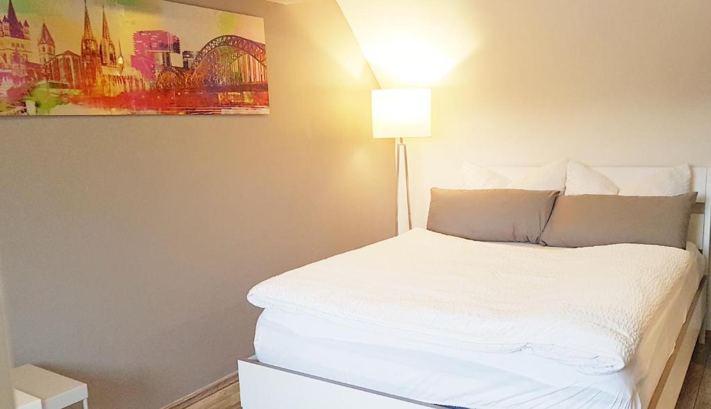 科隆Zwei schicke Apartments mit Parkplatz的卧室配有白色的床和灯