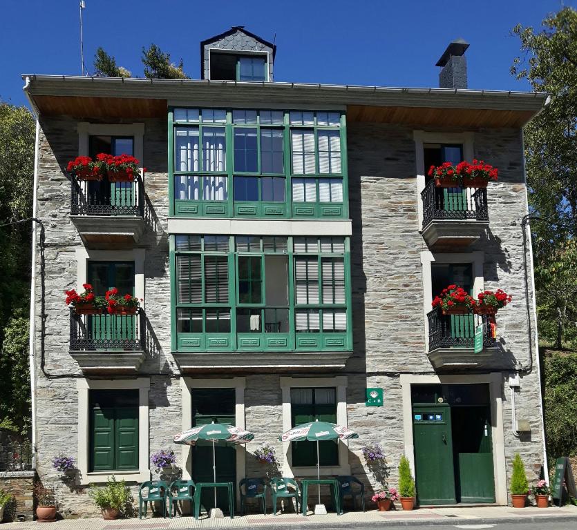 萨莫斯Casa Licerio的一座带绿色窗户和红色鲜花的阳台的建筑