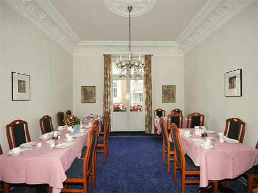 汉堡滨海大道酒店的用餐室配有粉红色的桌椅和吊灯。