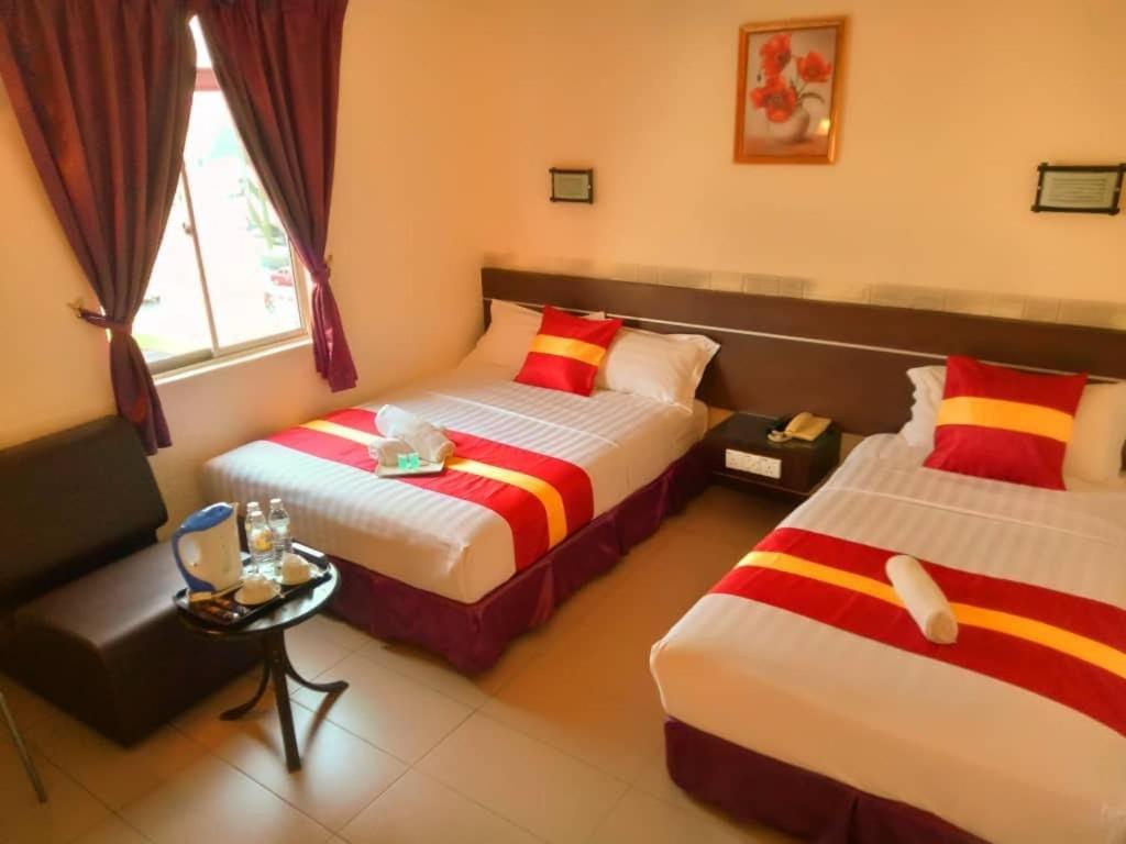 古晋城市旅馆的酒店客房设有两张床和一张桌子。