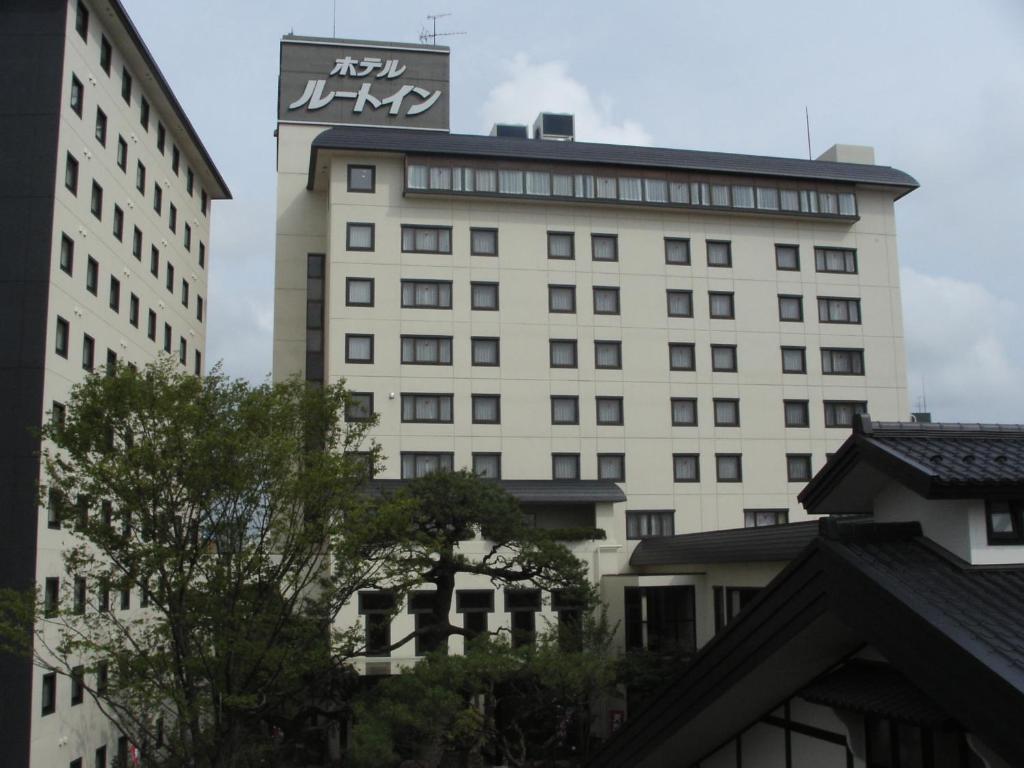 秋田格兰蒂亚路线秋田Spa度假经济型酒店的一座高大的白色建筑,上面有标志