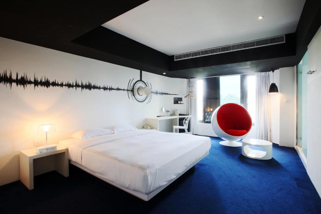 高雄Hotel Papa Whale-高雄美丽岛馆的一间卧室配有一张大床和一张红色椅子
