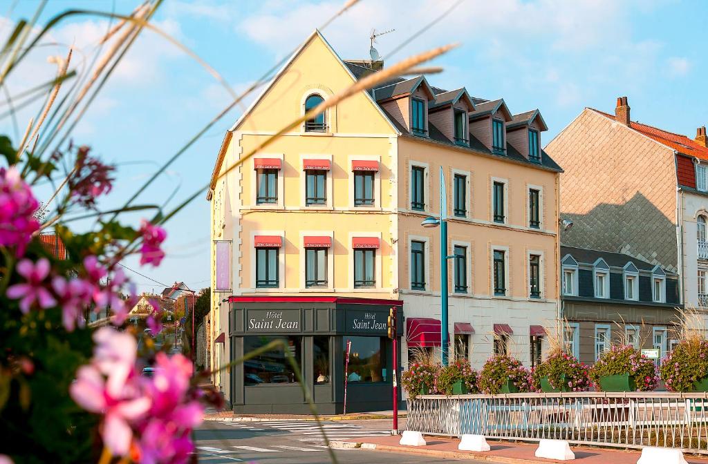 维姆勒圣简酒店的一条黄色的建筑,位于一条拥有粉红色花卉的城市街道上