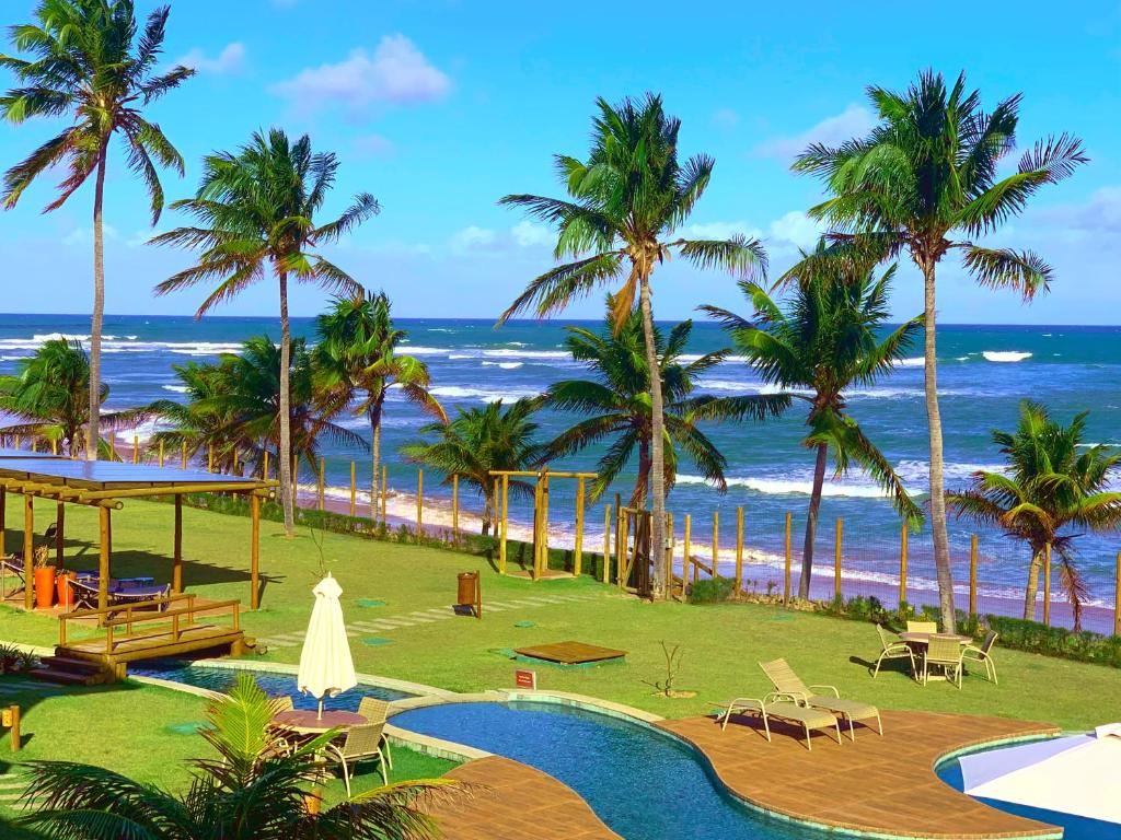 伊塔齐米林Apartamento beira-mar no Bali Bahia的拥有游泳池、棕榈树和海洋的度假胜地