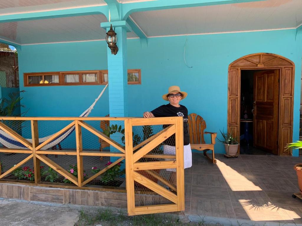 MariabéHostal Mi Castillo的坐在蓝色房子前面椅子上的男人