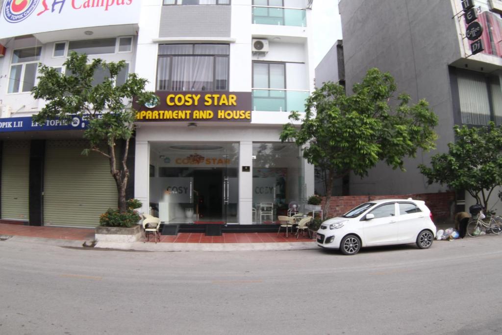 海防Cosy Star Apartment and Motel的停在大楼前的白色汽车