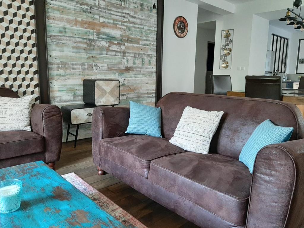 勒布罗伊斯Le Manoir, appartement Onyx的客厅配有棕色沙发和蓝色枕头。