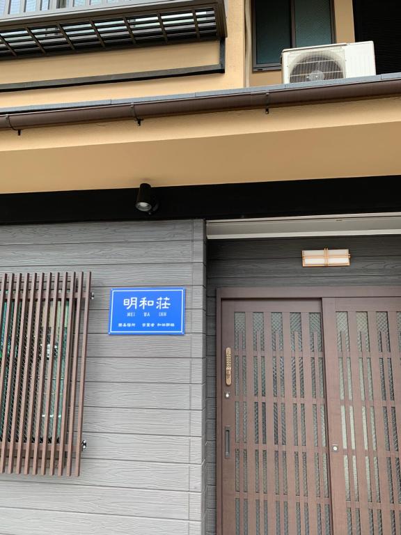 京都明和荘Mei Wa Inn的建筑物的门,上面有标志