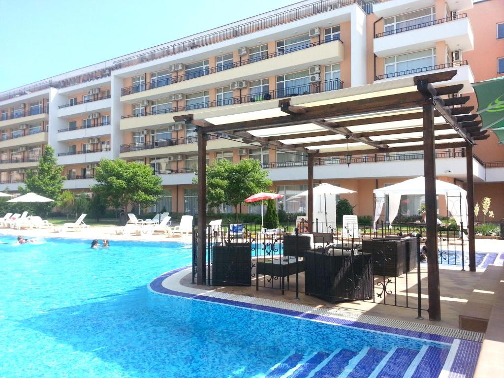 阳光海滩米娜达格兰德咖米莉亚公寓酒店的一座带桌椅的游泳池以及一座建筑