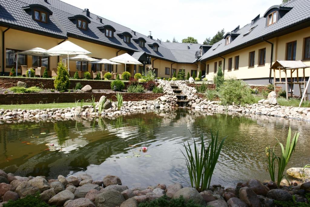 SuchedniówHotel Paradiso的一座建筑前有池塘的酒店