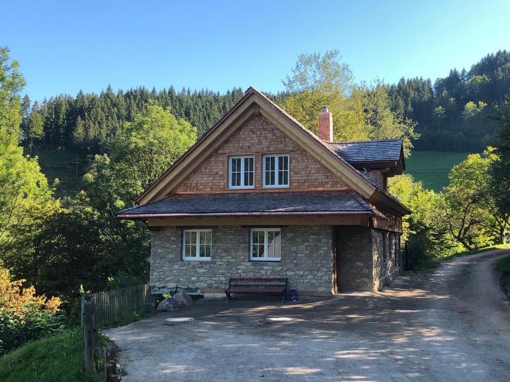 西蒙斯瓦尔德Ferienhaus Haldenmühle - traumhafte Lage mitten in der Natur mit Sauna的路边有长凳的砖房