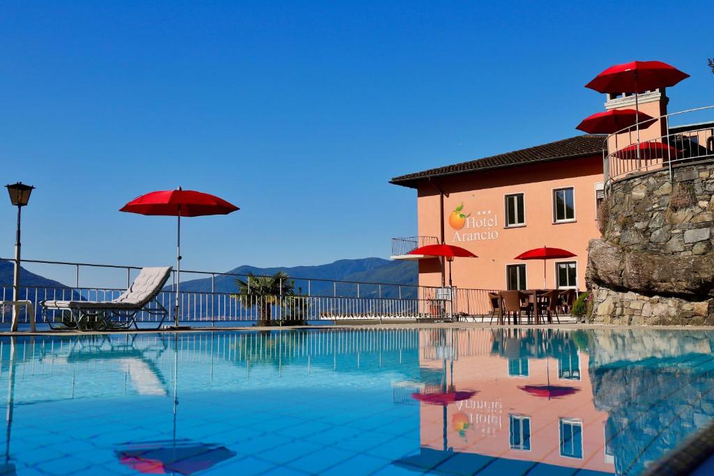 阿斯科纳阿兰西奥酒店的一个带红色遮阳伞的游泳池和一座建筑