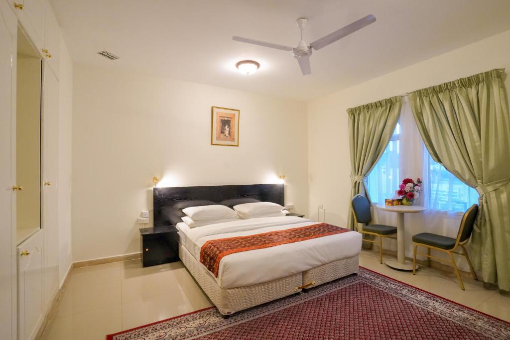 马斯喀特Hotel Summersands Al Wadi Al kabir的卧室配有一张床和一张桌子及椅子
