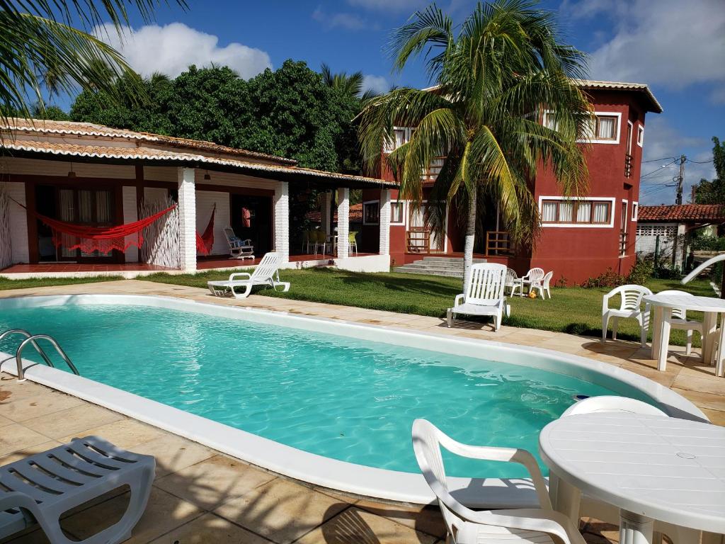 圣米格尔-杜戈斯托苏RANCHO GOSTOSO POUSADA的一个带桌椅的游泳池和一个房子