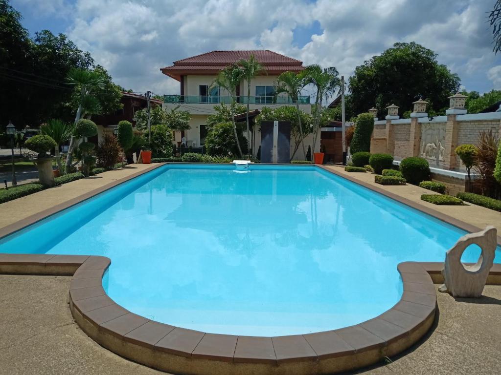 信武里府苏玛里别墅旅馆的一座大型蓝色游泳池,后面有一座房子