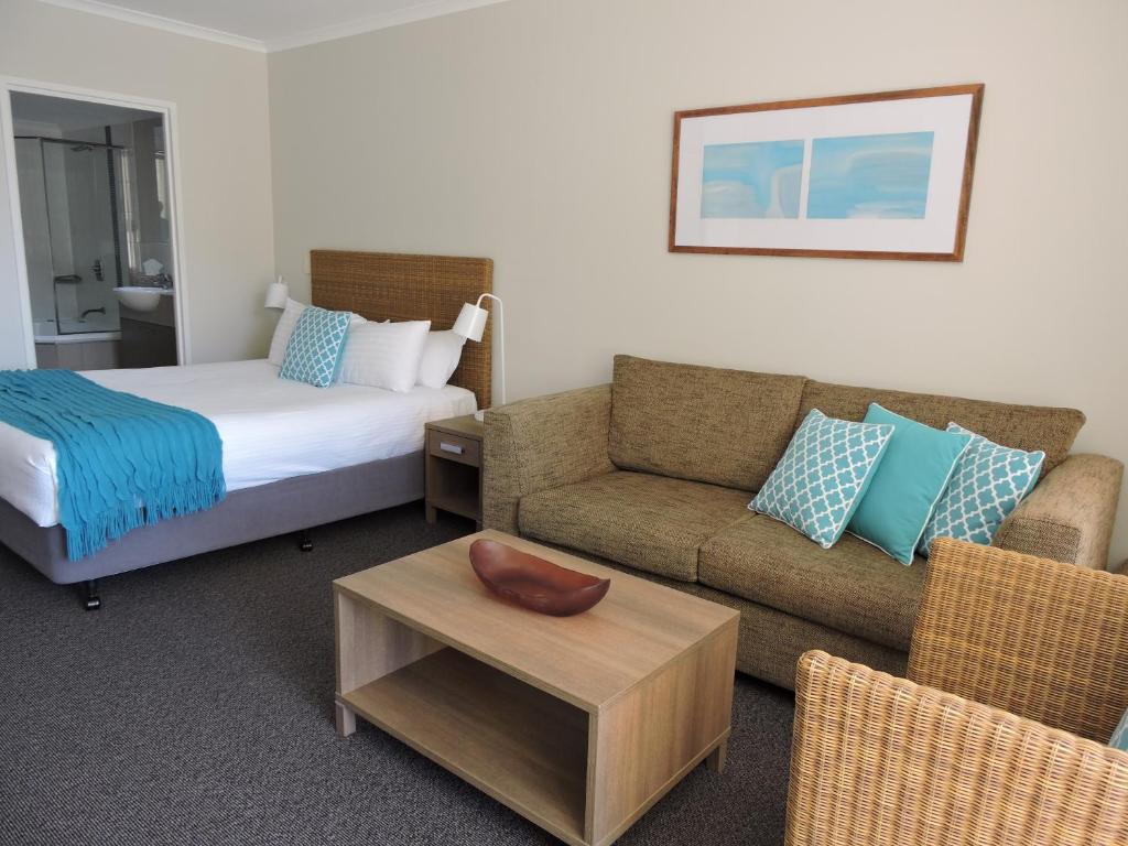艾塔龙海滩BASE Holidays - Ettalong Beach Premium Apartments的酒店客房配有床、沙发和桌子。