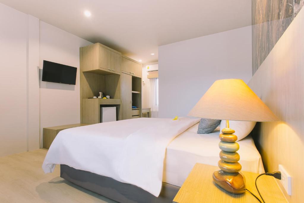 卡塔海滩幻想山简易别墅酒店的一间卧室配有一张床和一张桌子上的台灯