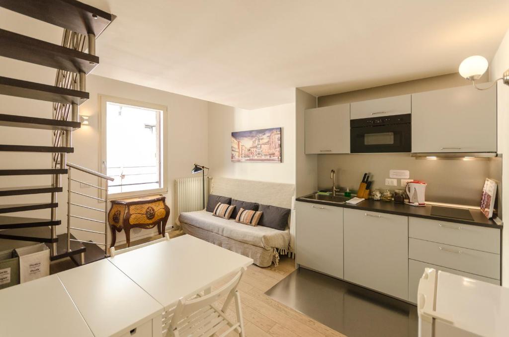 博洛尼亚Appartamento del Nettuno的一间带白色橱柜的厨房和一间客厅