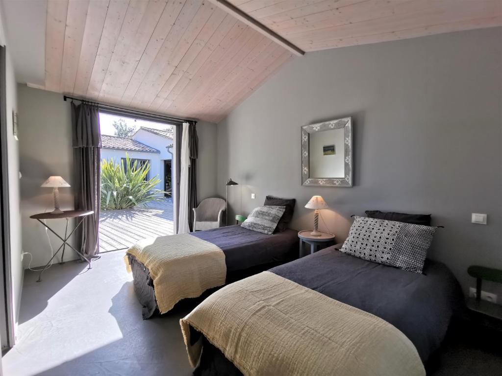 雷岛林滩Derrière la plage : suite, patio et pergola的一间卧室设有两张床,并设有一个通往庭院的门。