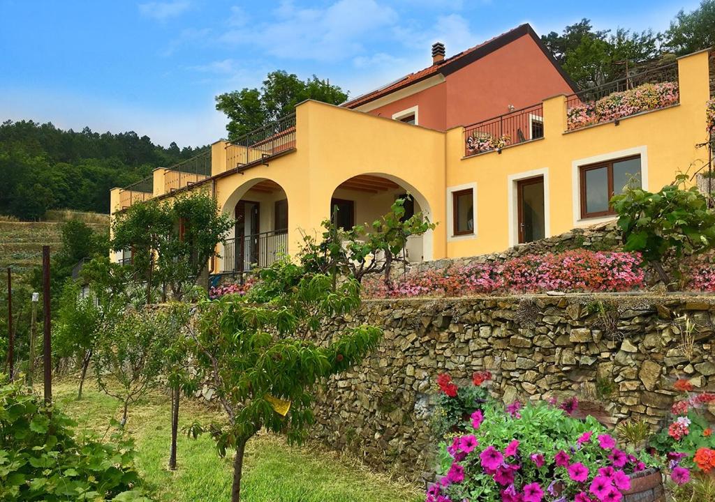 Tovo San GiacomoAgriturismo LaValleggia的花朵的石墙顶部的房子