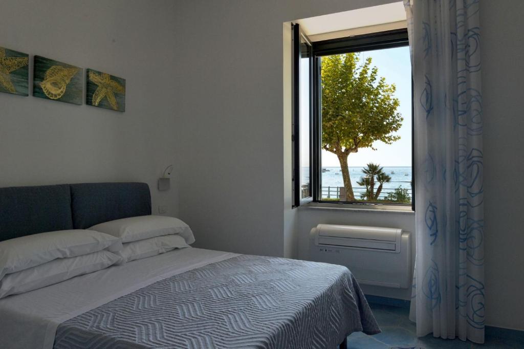 马奥莱Una Finestra sul Mare的一间卧室设有一张床,窗户有树