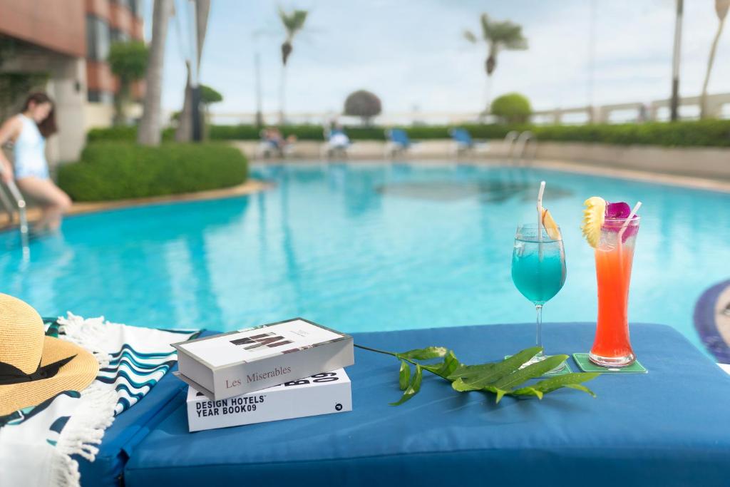 曼谷The Emerald Hotel - SHA Extra Plus的池畔桌子和饮料