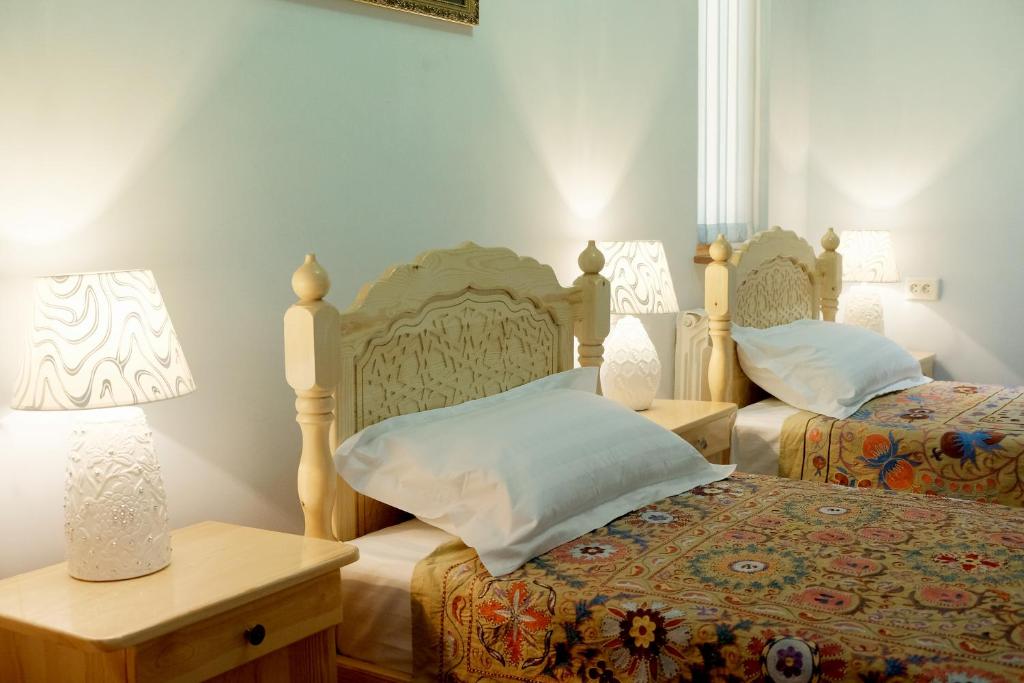 布哈拉Ismail的一间卧室设有两张床和一张带台灯的桌子。