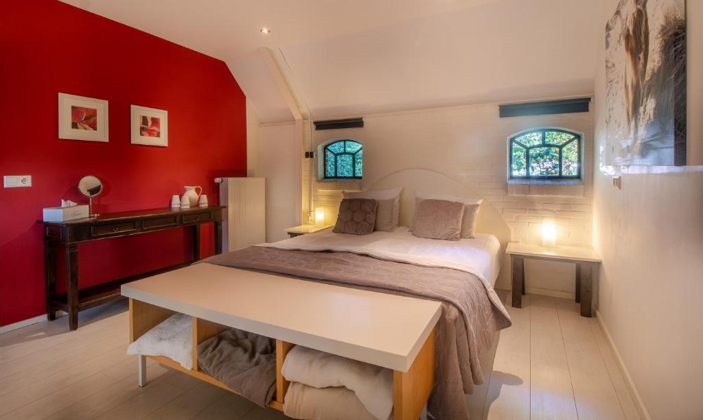 Veeningen珠实伦特住宿加早餐旅馆的一间卧室配有一张红色墙壁的床和一张书桌