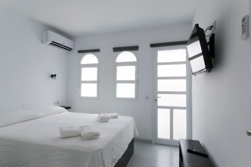 圣巴托洛梅bungalow with terrace near the beach的白色的客房设有一张床和两个窗户。