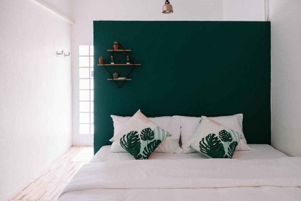 素叻Baannokhook Home&Cafe的一间卧室设有绿色的墙壁和一张带枕头的床