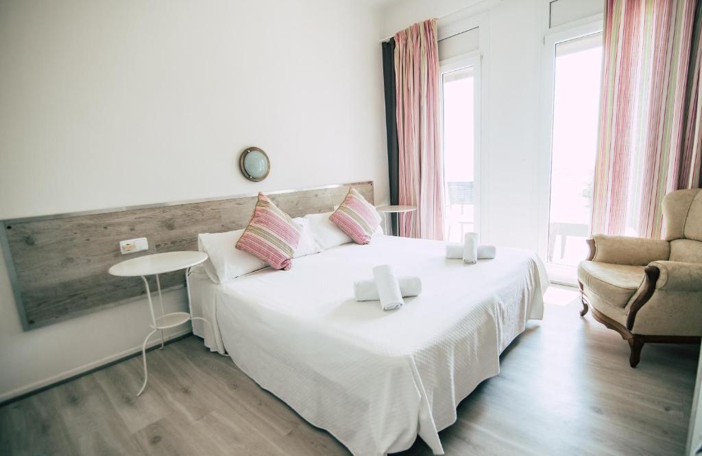 雅弗郎其Hostal La Llagosta的卧室配有一张白色大床和一把椅子