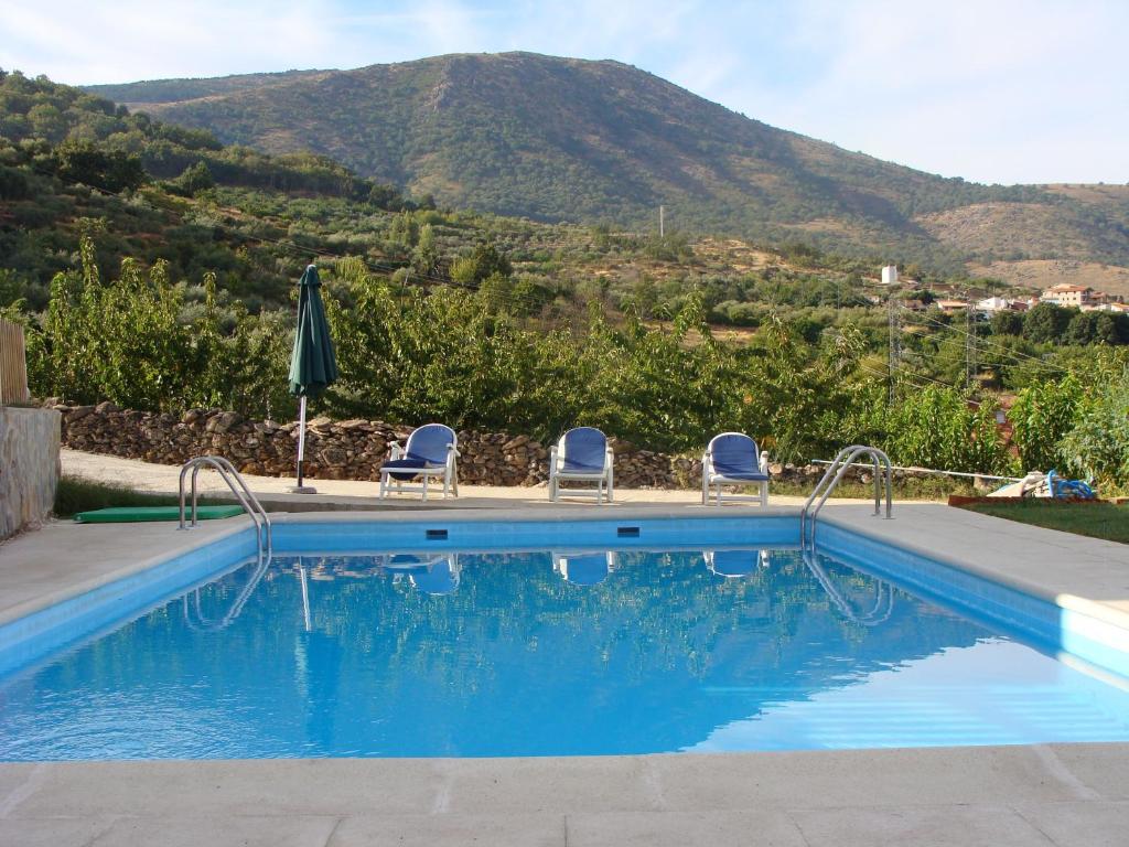 Casas del MonteCasas Rurales Manolo的一个带椅子的游泳池,后方是一座山
