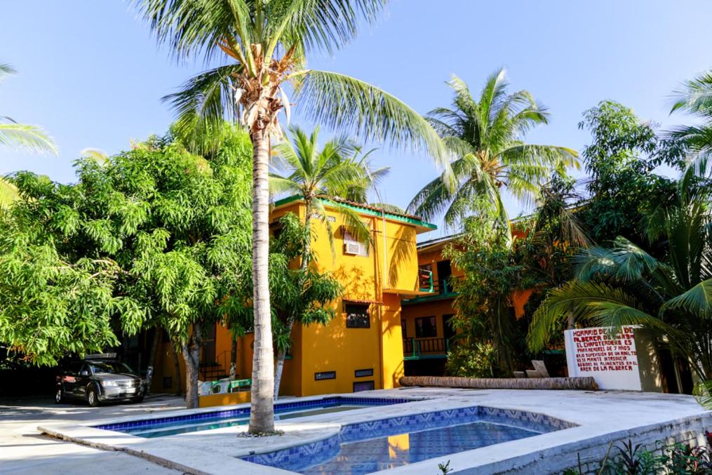 埃斯孔迪多港Hotel Posada Playa Manzanillo的棕榈树和游泳池的黄色房子