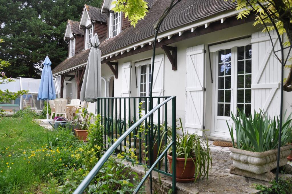 圣雷格勒Chez Cyril et Vi的一座带雨伞和一些植物的白色房子