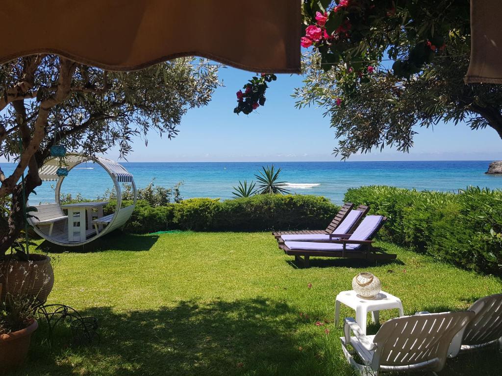 格利法达Corfu Glyfada Beach Apartment 13的一个带两把椅子和秋千的院子和大海