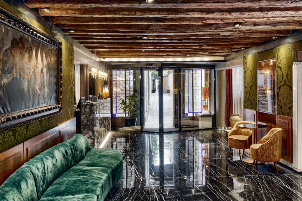 威尼斯比三兹奥酒店的客厅配有绿色沙发和桌子