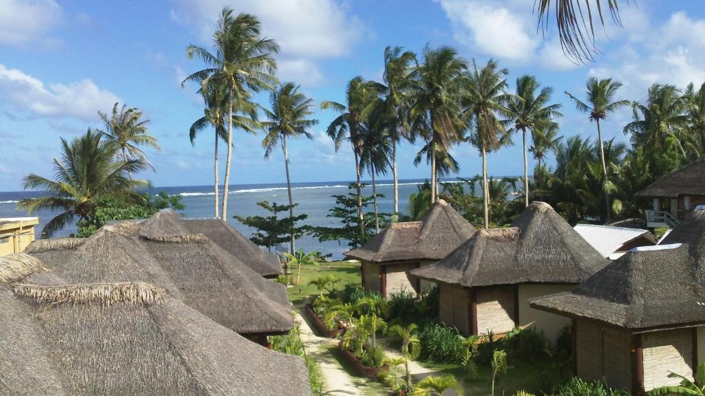 卢纳将军城Jonas and Twins Resort的享有带茅草屋顶的度假胜地和大海的景致。