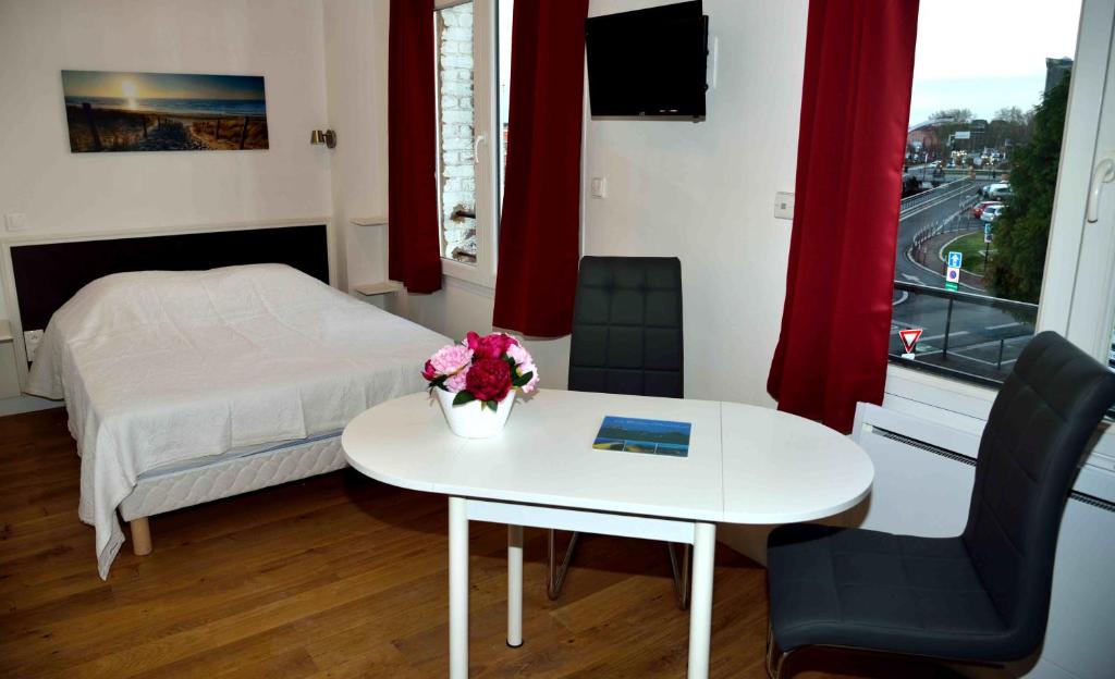 杜埃Apparthotel Douai Gare的一间卧室配有一张床和一张鲜花桌子