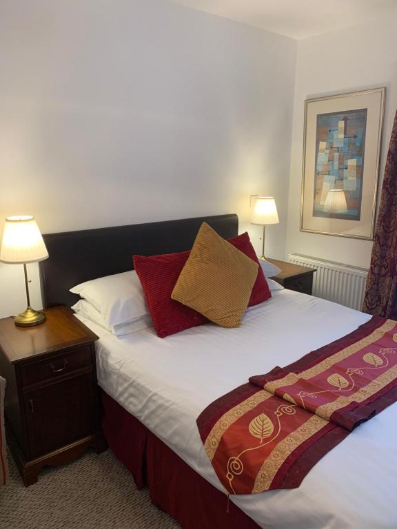 格雷夫森德Jessamine House Hotel的卧室配有一张带红色和金色枕头的大床