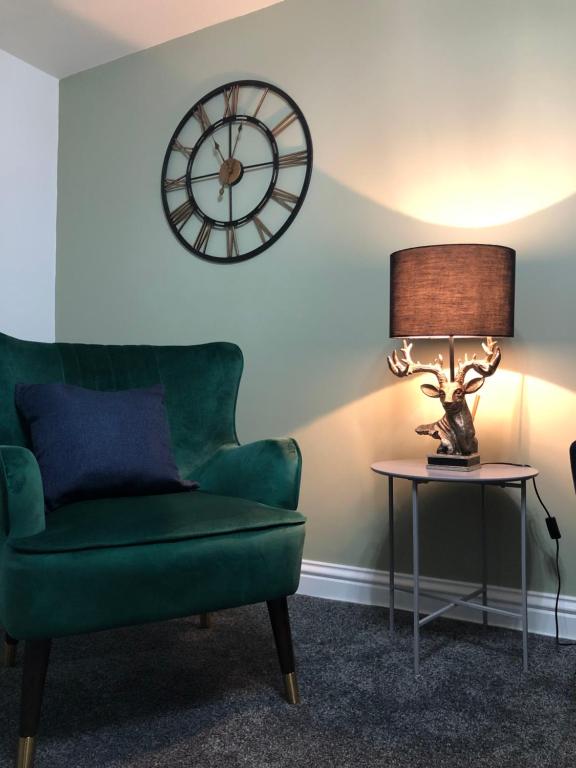 艾尔The Nook - Coorie Doon的客厅配有绿色沙发和时钟