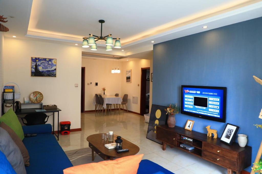 Xiazangtuan阅海民宿青岛北站海景公寓的客厅设有蓝色墙壁和电视。