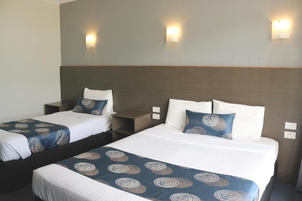阿德莱德The Sands Motel Adelaide的酒店客房带两张带蓝白色枕头的床