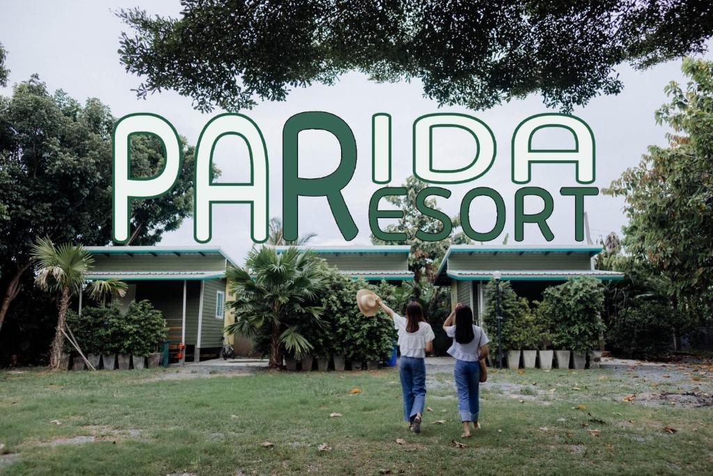 信武里府Parida Resort的两名妇女站在公园标志前
